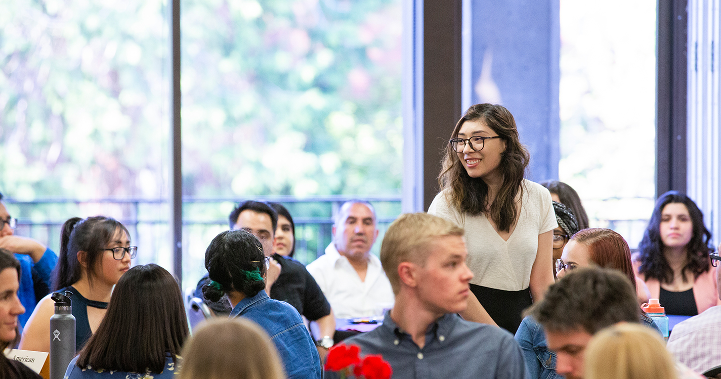 Student stands smiling in Cat Cavern after receiving an award