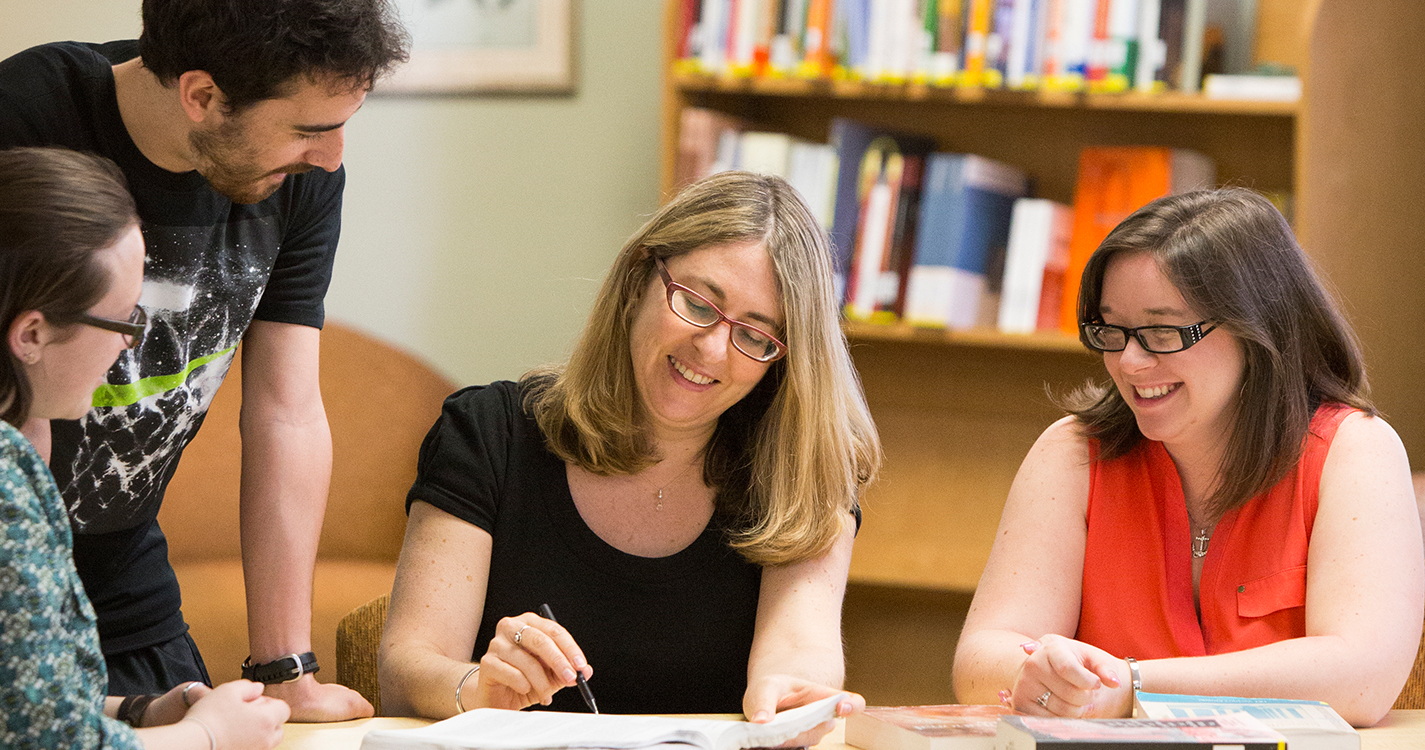 Professor of Law Laura Appleman sits at a table with three students having a discussion