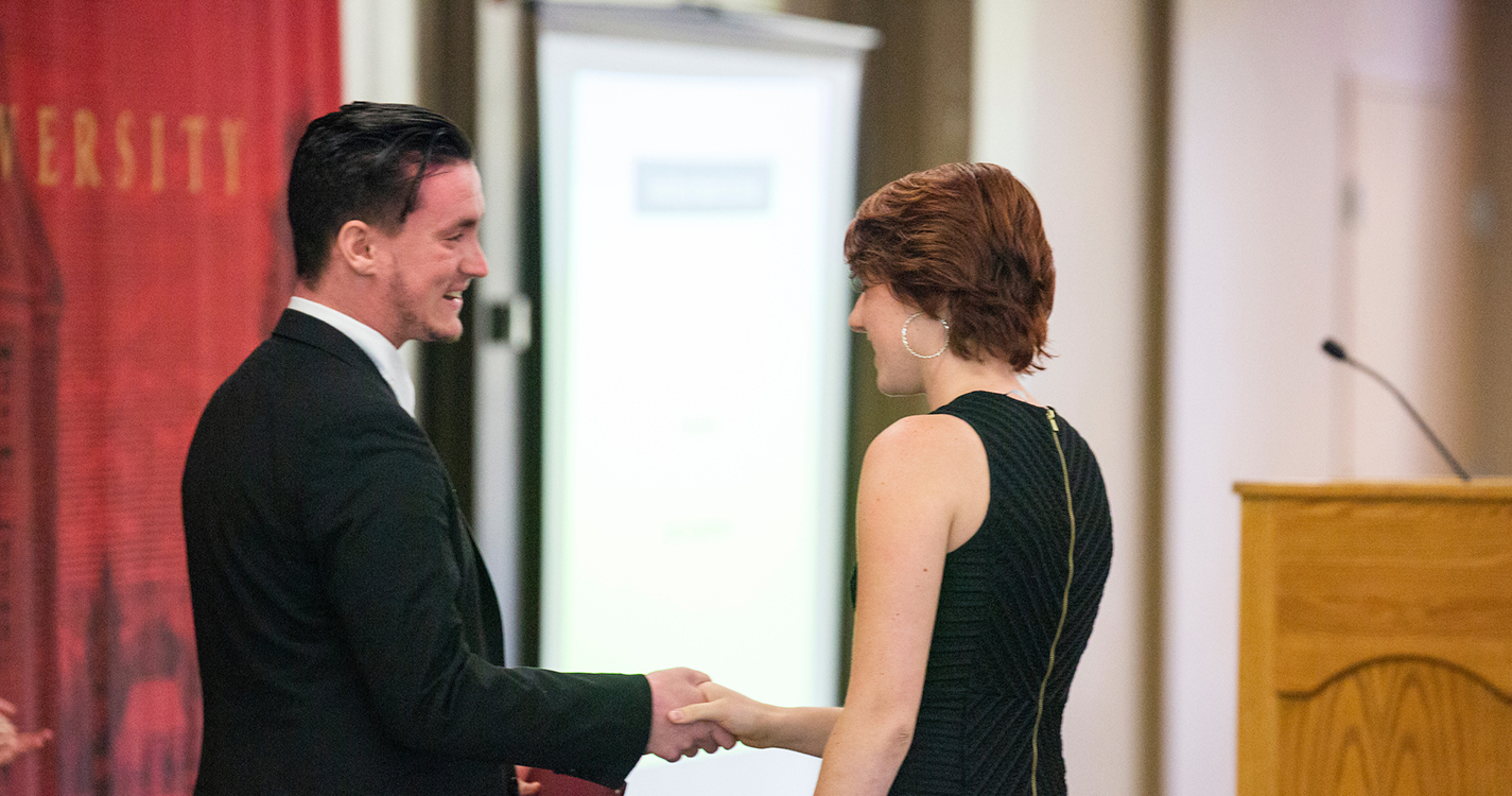 students shake hands after one receives an award