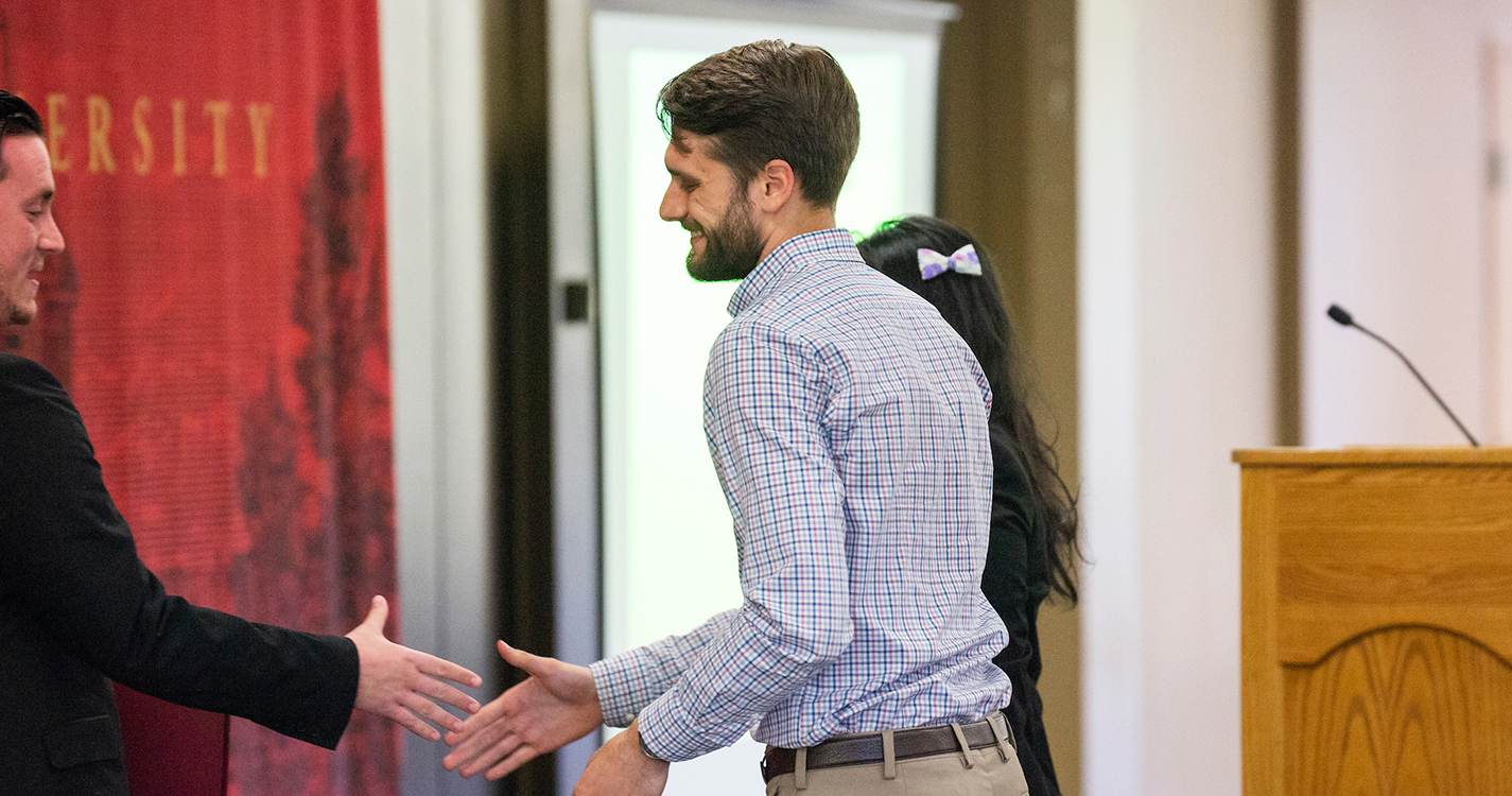 students exchange a handshake during awards ceremony