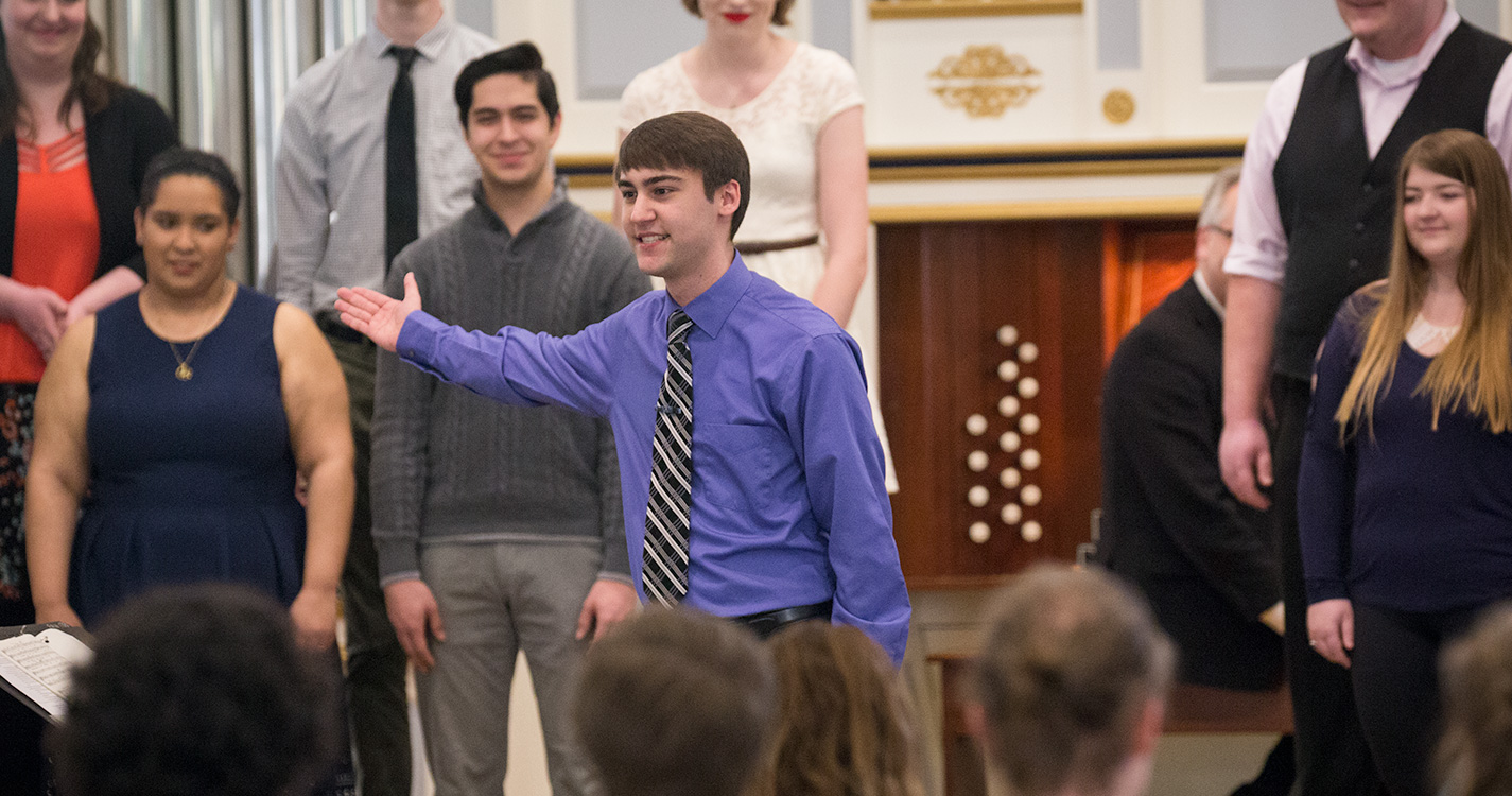 A student presents a choir of singers at Student Scholarship Recognition Day. 