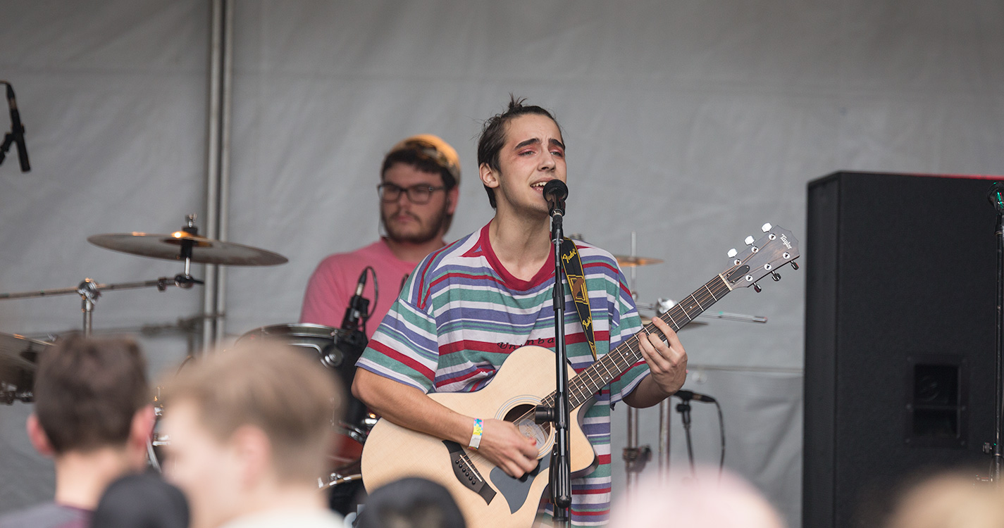 A guitarist sings onstage.