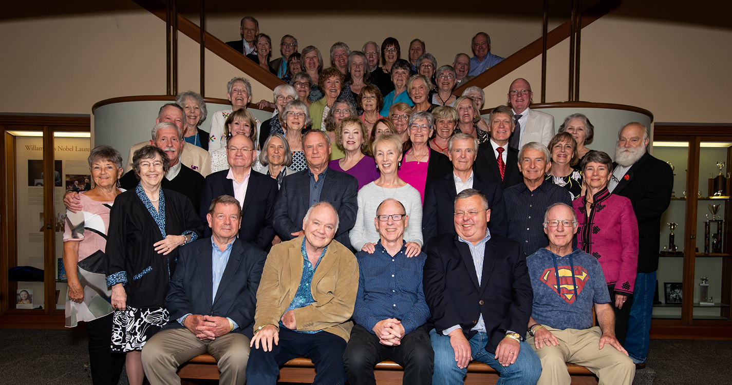 a class of alumni stand on steps 