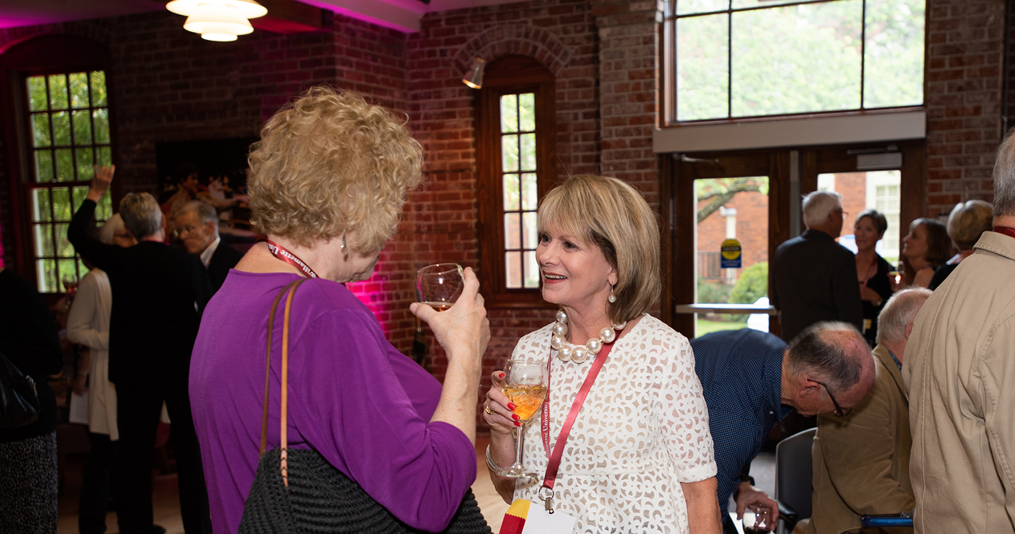 alumni stand talking to each other in the lobby of Pelton Theatre