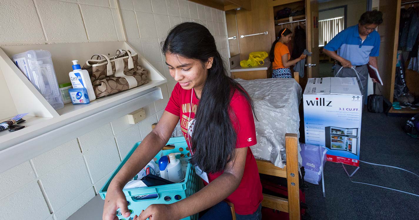 A student unpacks in a residence hall room.