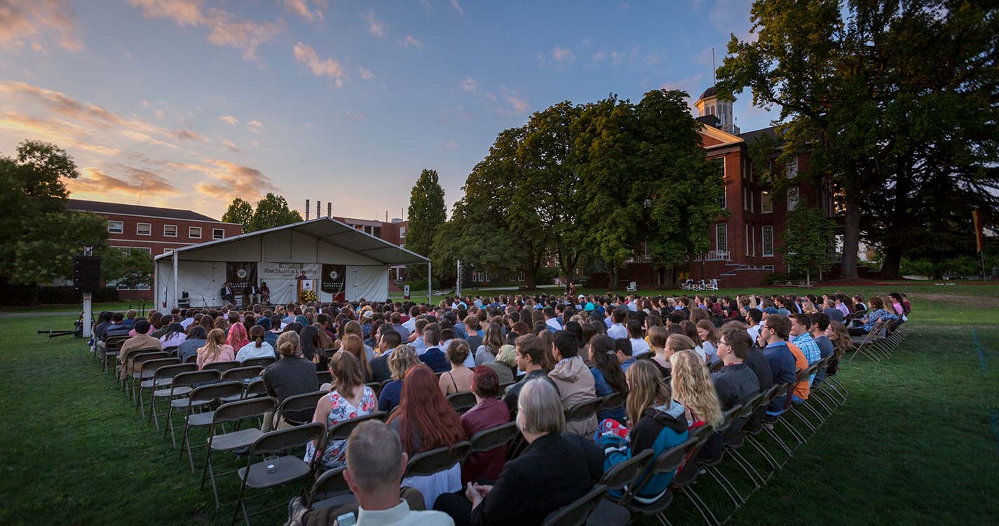 The entire new class of Bearcats sits in rows of chairs on the Quad facing a covered stage.