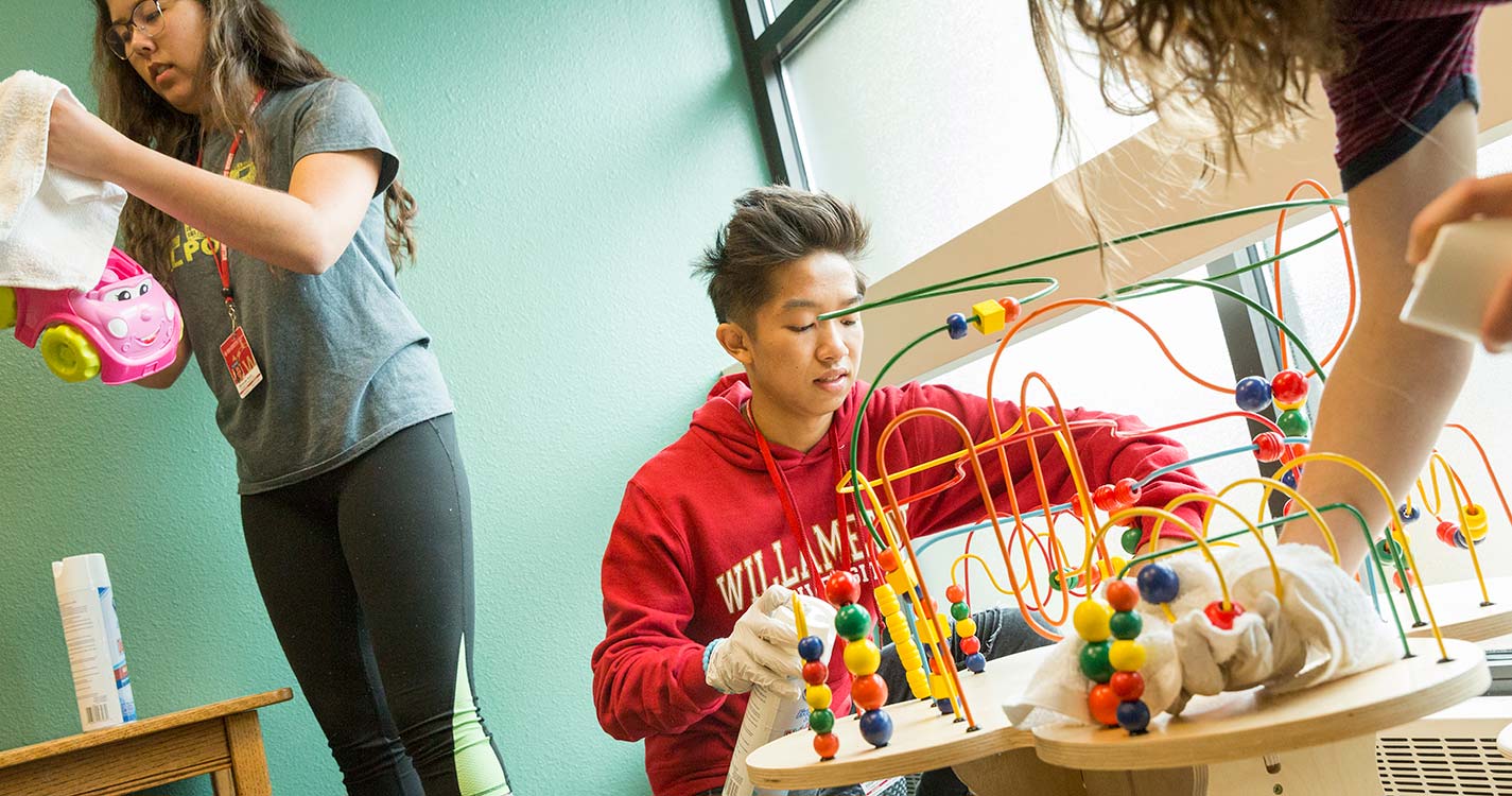 A student sanitizes a toy at the Center for Hope and Safety during Bearcats Give Back