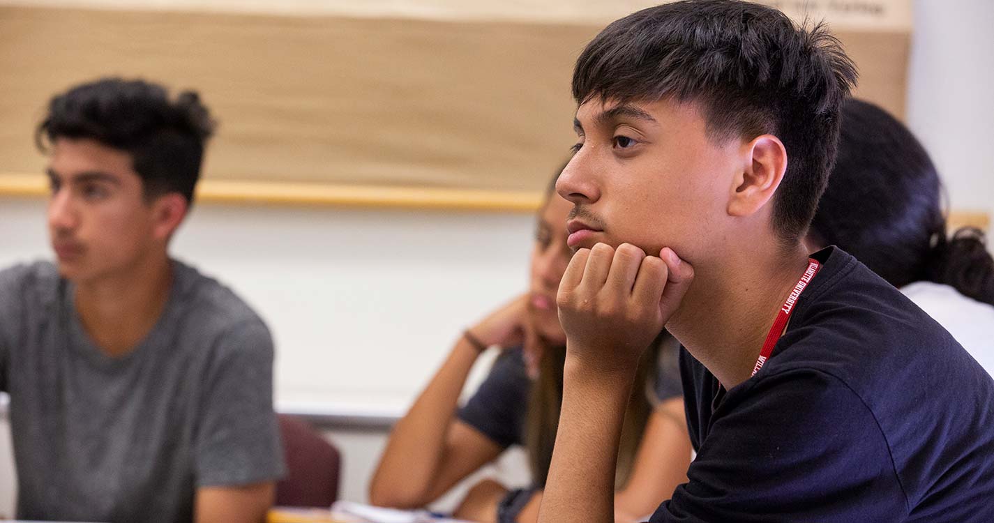 A student sits pensively at a desk