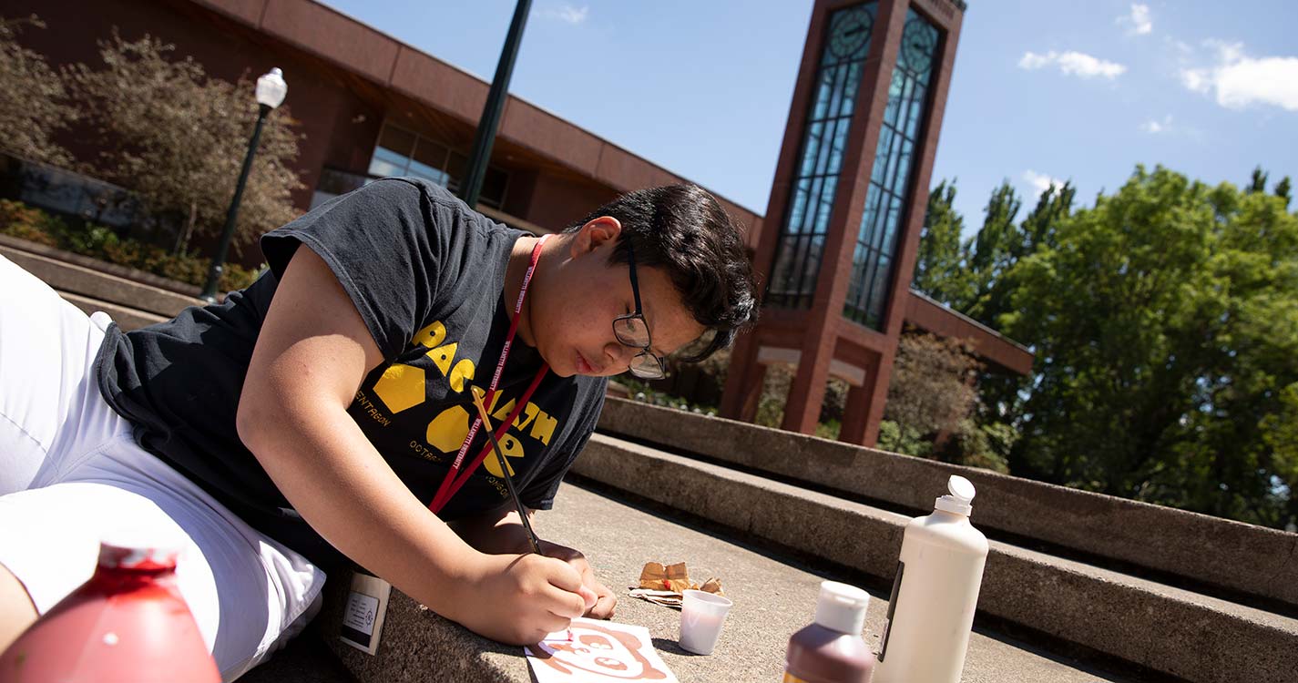 A student reclining on the pavement works in a notebook in Jackson Plaza