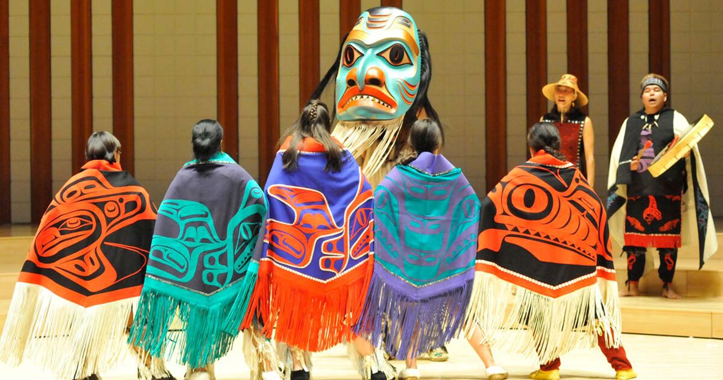 Native American dancers in brightly colored clothing at a performance. 