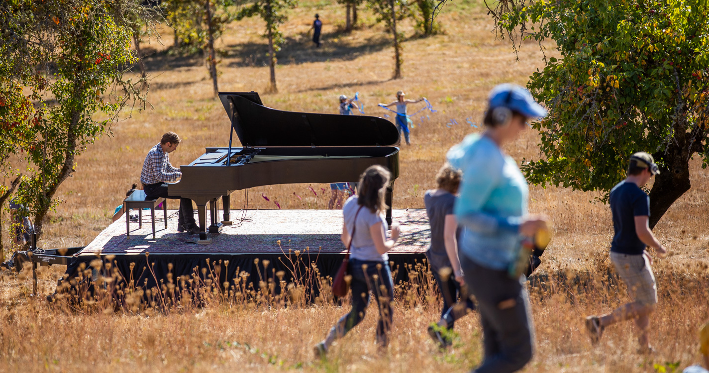 Hunter Noack plays a grand piano in the middle of a field at Willamette's Zena campus