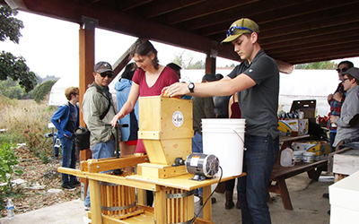 Two students work at a cider press