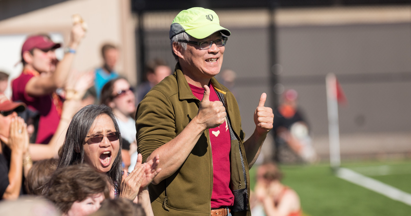 A fan gives a thumbs up from the sideline of the soccer field