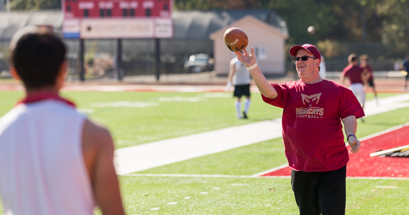 A father throws a football to his Bearcat son who is warming up for the game