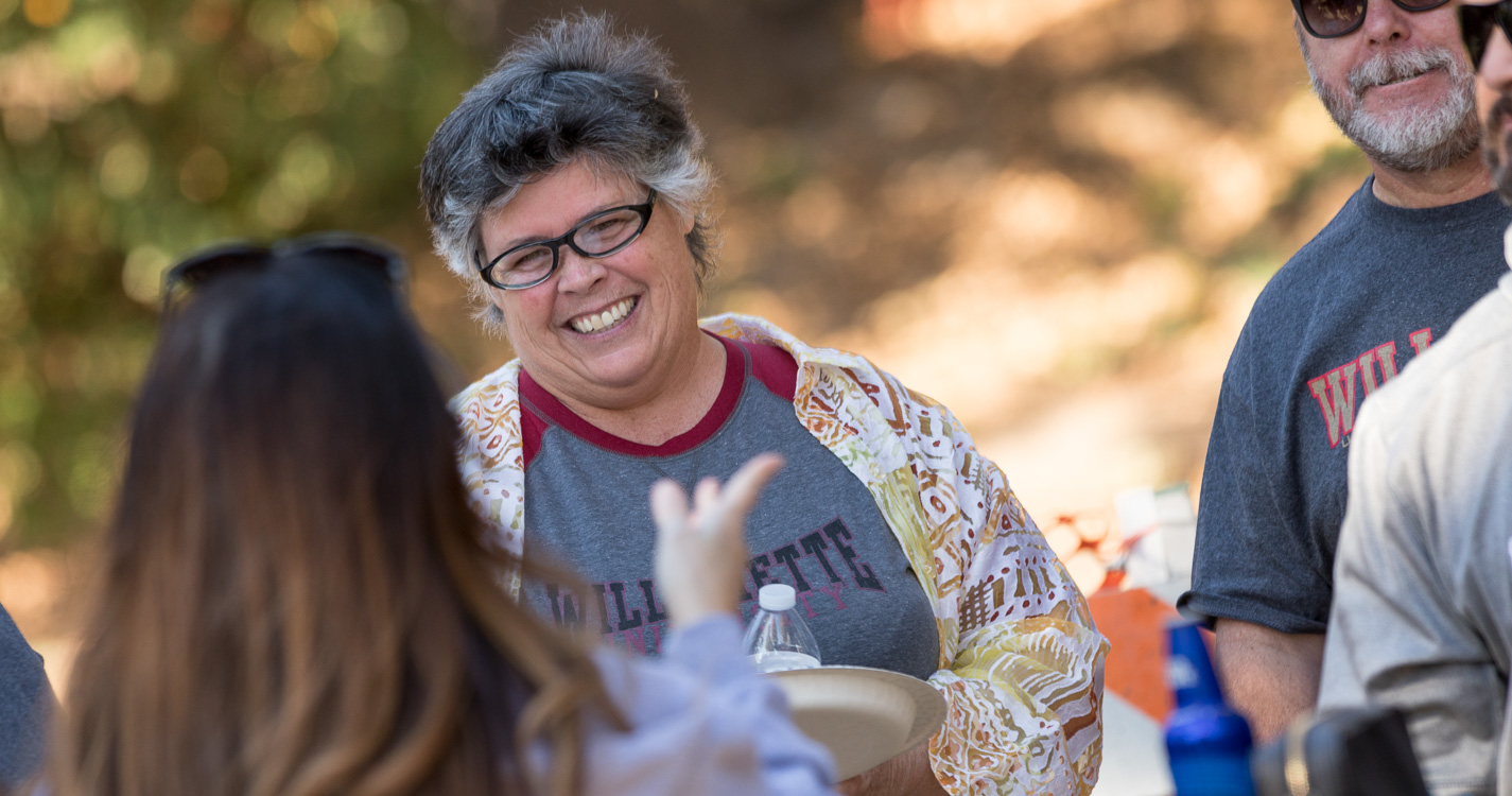 People conversing and smiling while sitting at a picnic table