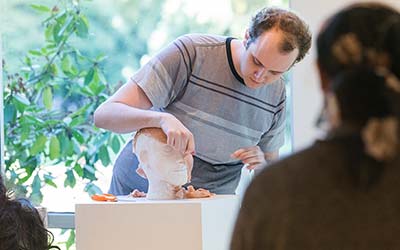 Student shows off sculpture at art opening. 