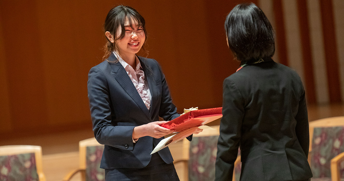 Student smiles holding a gift wrapped in red