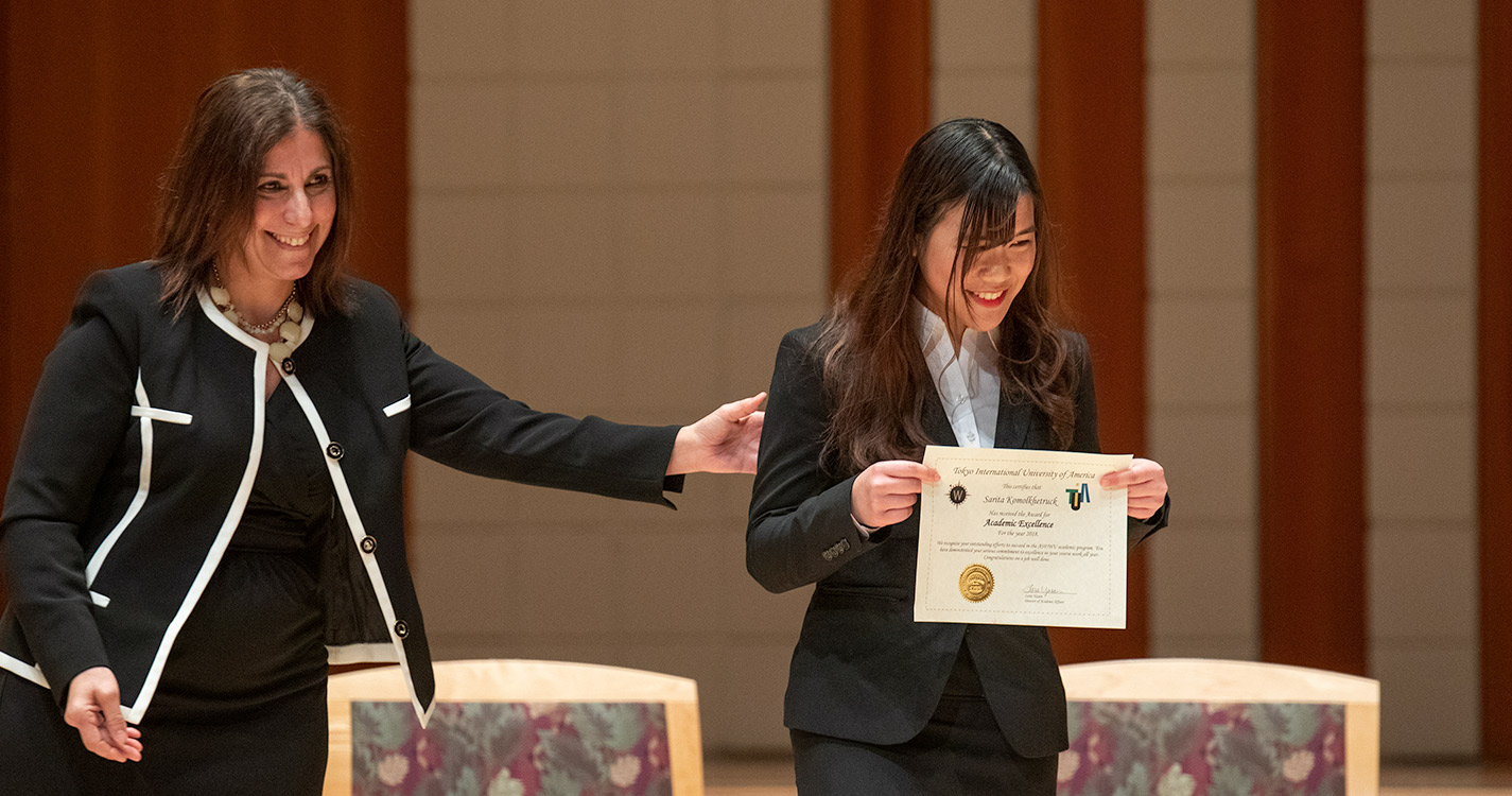 Student smiles holding a certificate