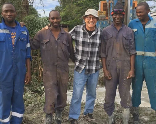 Jon Steiner and four men stand before a well drill