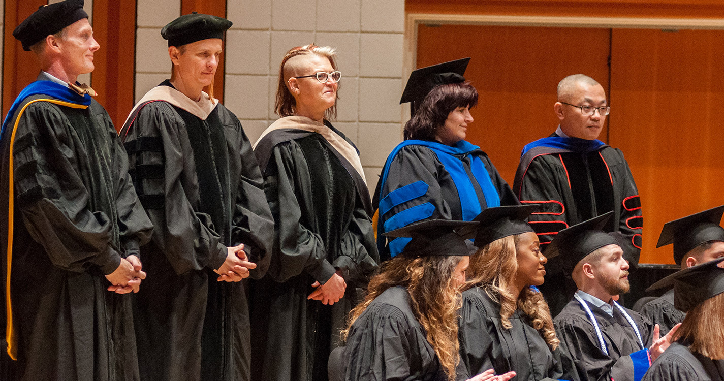 Graduates wait on stage to receive their diplomas