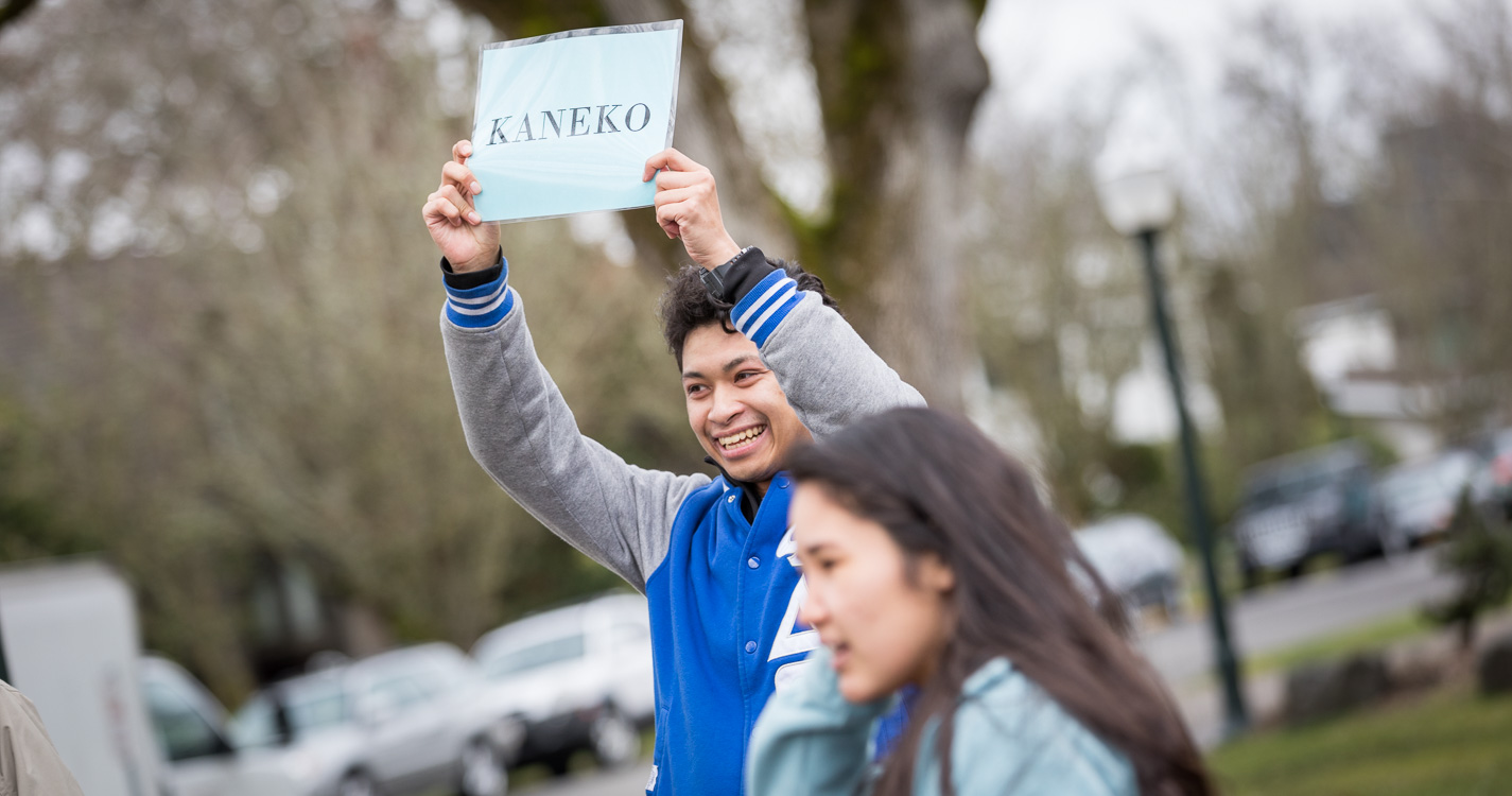 Student holding a small sign that says Kaneko