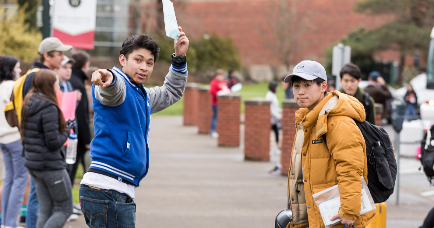 Student points the way down the sidewalk for a new student