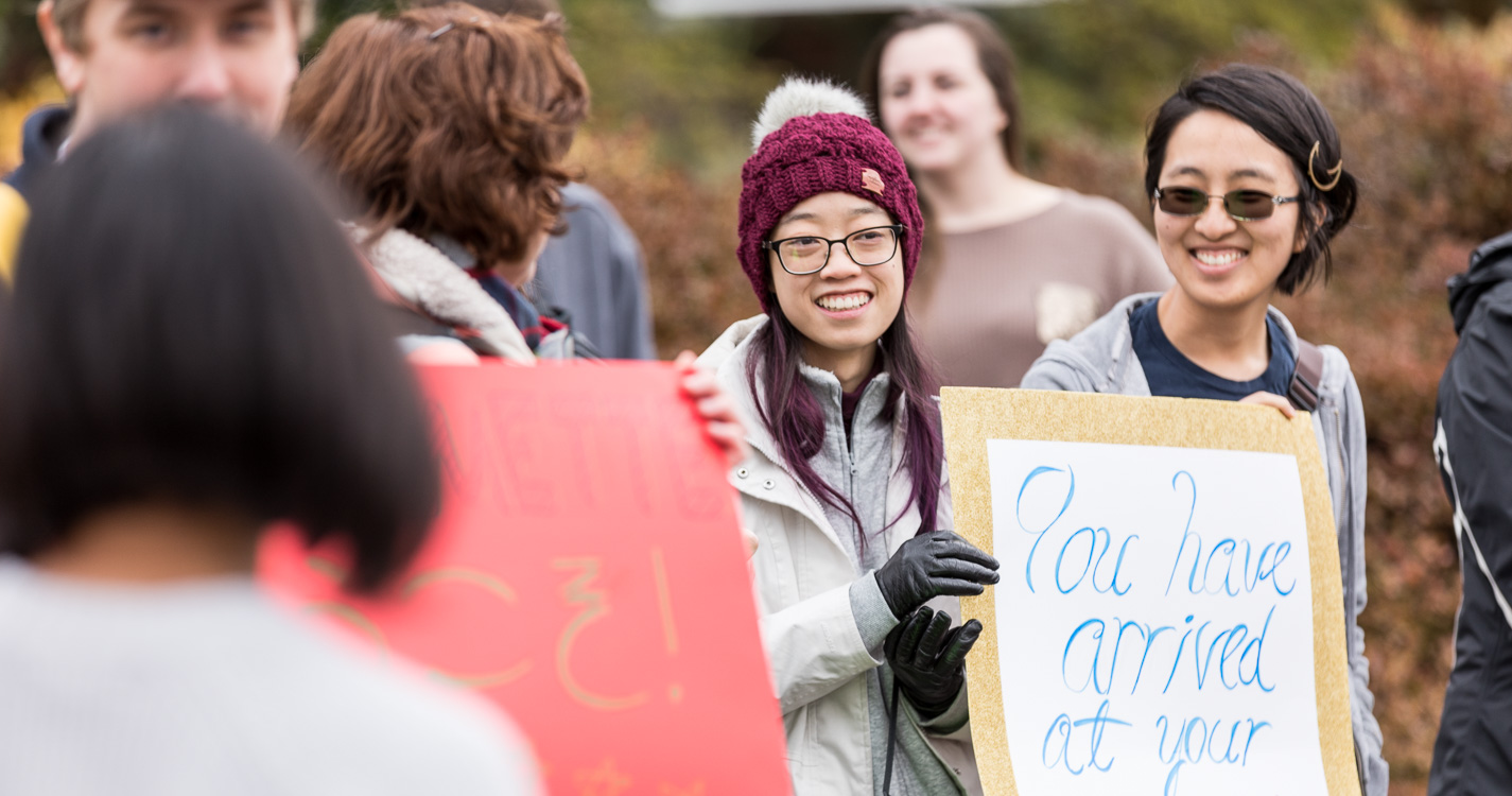 two students holding a white welcome sign