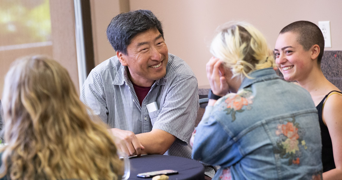 Professor and student sit at a table smiling