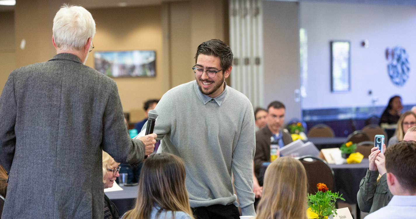 student shakes a professor's hand