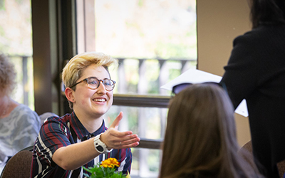 smiling student reaches for an award certificate