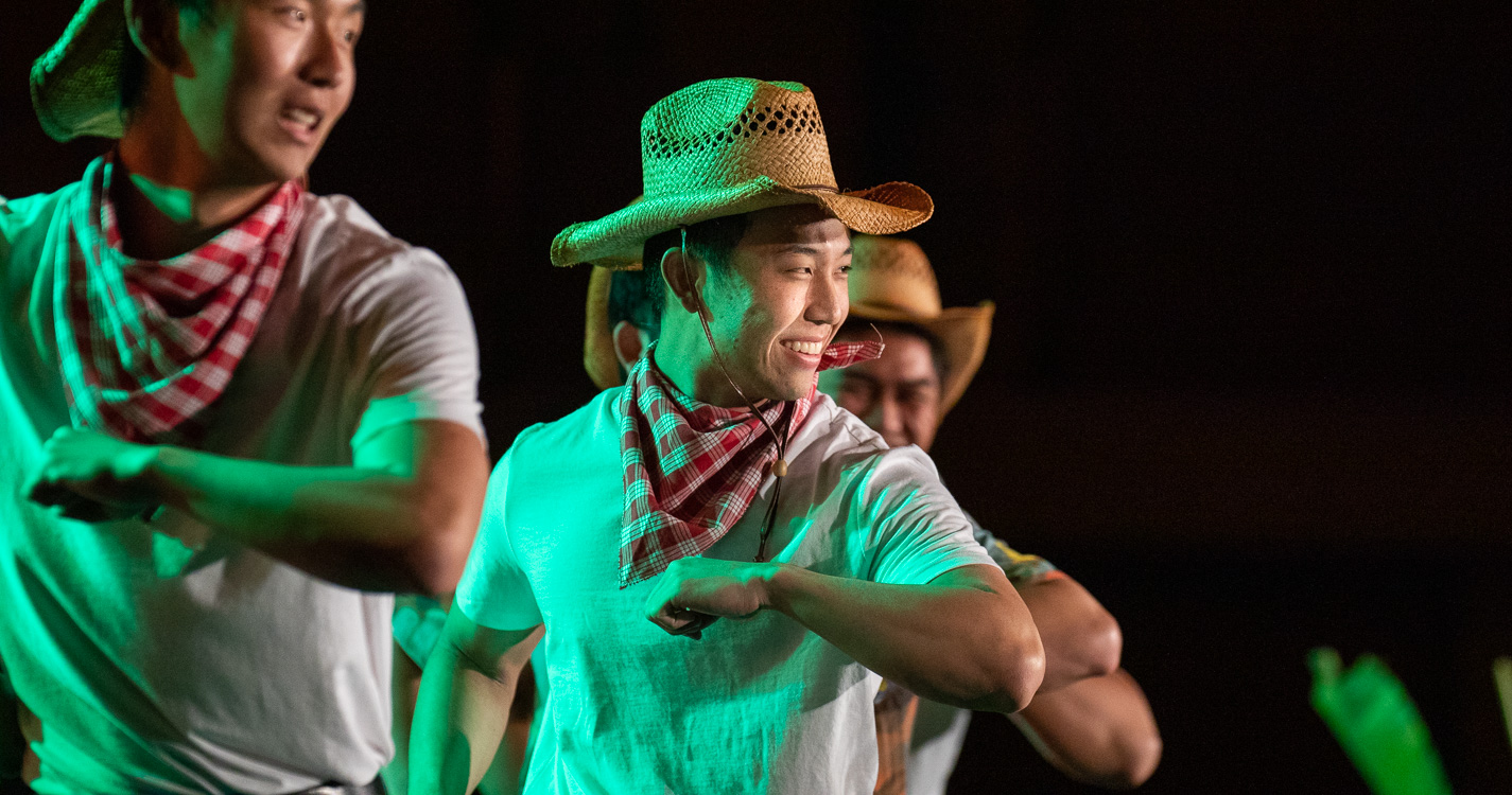 Students in straw hats dancing