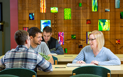 law students converse at a table in the law library