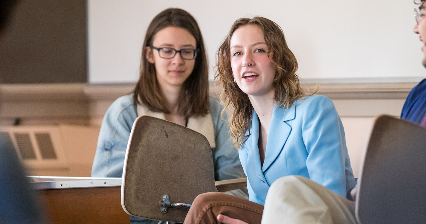 Student sitting in a desk in a classroom speaks