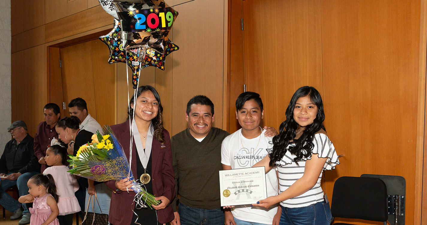 Graduate holding flowers and balloons poses with guests