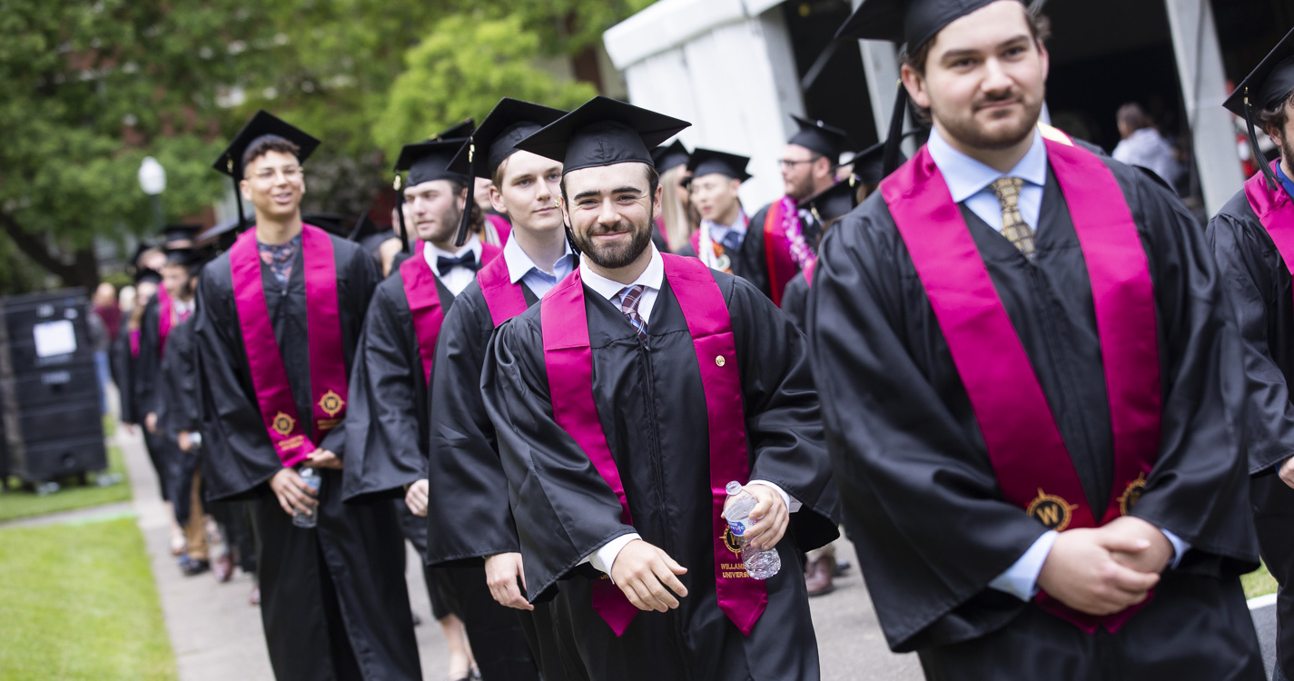 Students dressed in caps and gowns walk in the commencement procession.