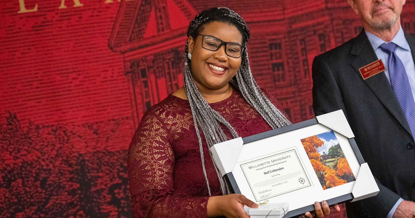 Smiling student holds an award plaque