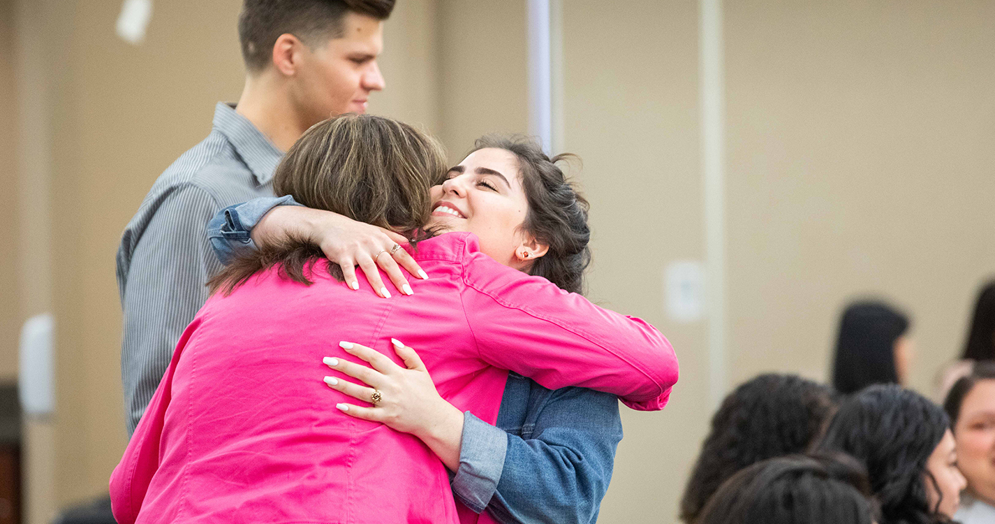 Student receives hug from staff member when receiving award