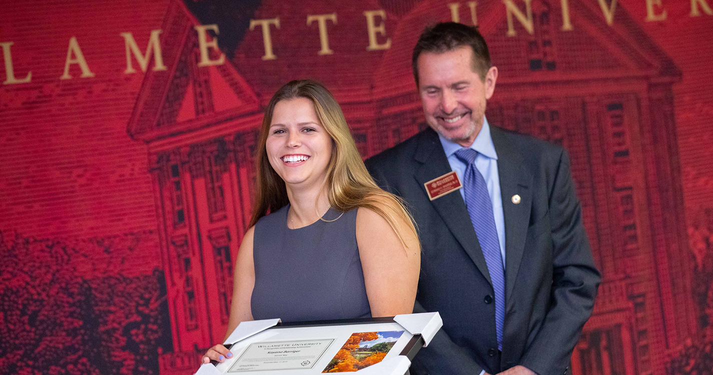 Smiling student holds an award plaque