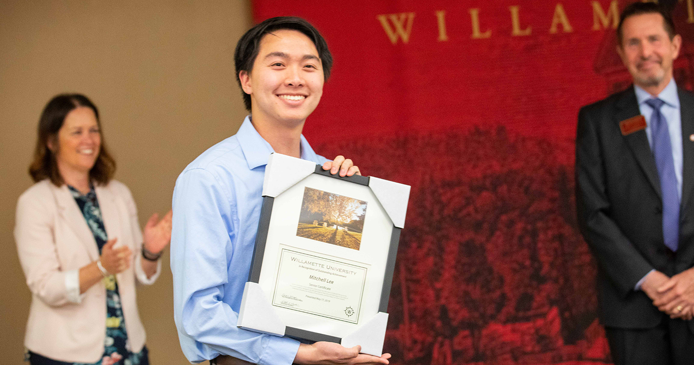 Smiling student holds an award plaque