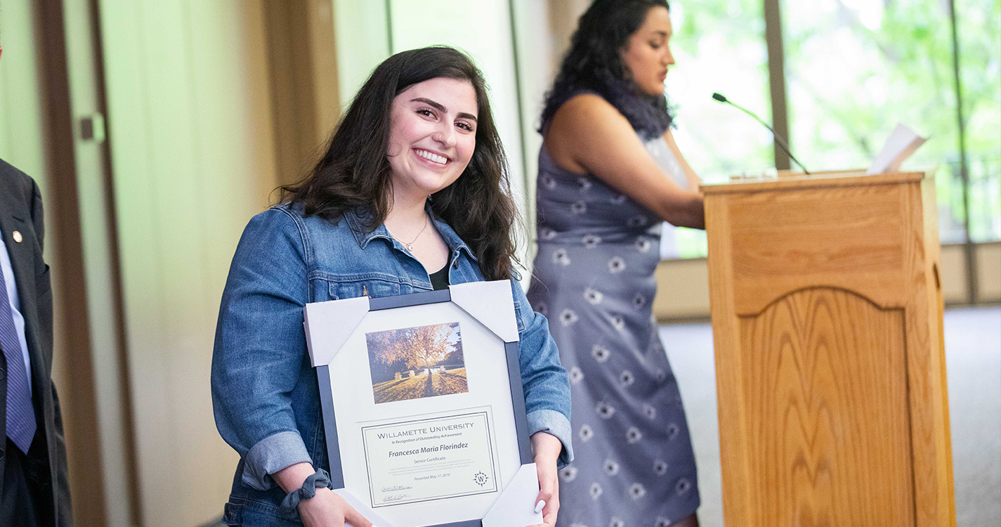 Smiling student holds an award plaque