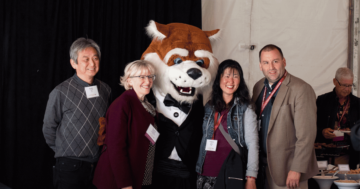 Four alumni pose with Blitz in a tuxedo