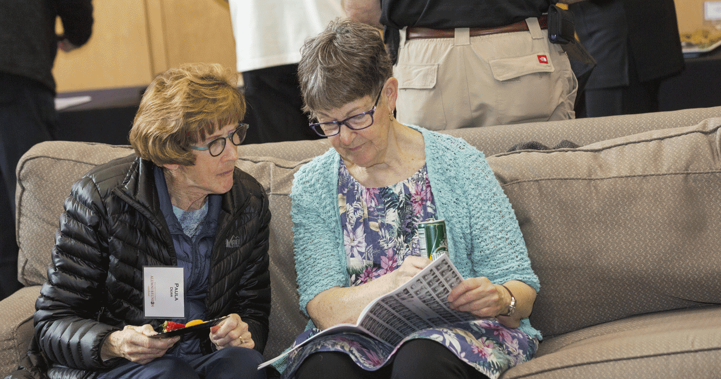 Two alumni look at a brochure