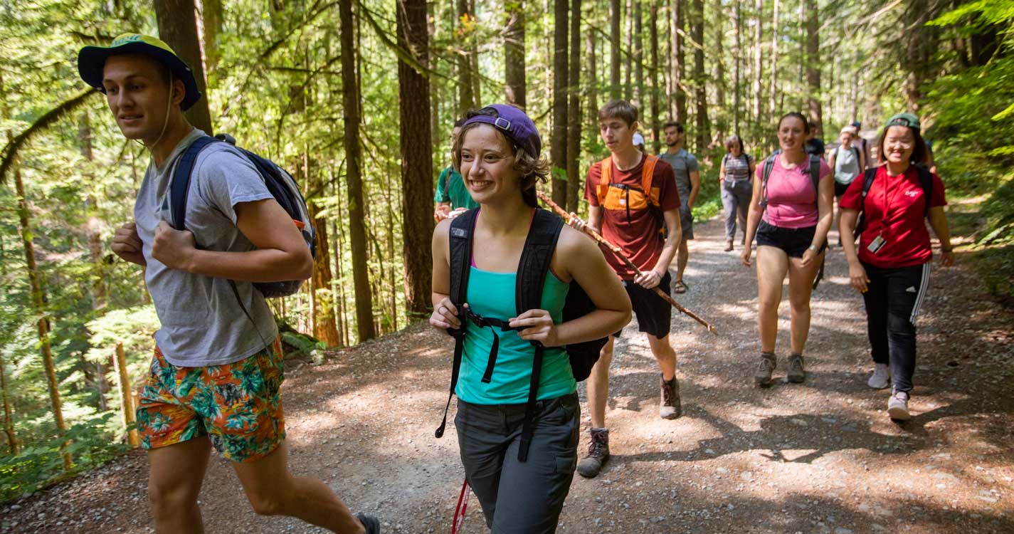 students hike on a trail in the woods