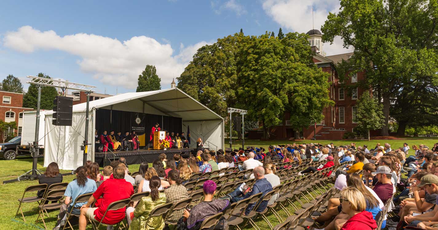 From a covered stage on the Quad, President Thorsett speaks to a seated crowd before Waller Hall