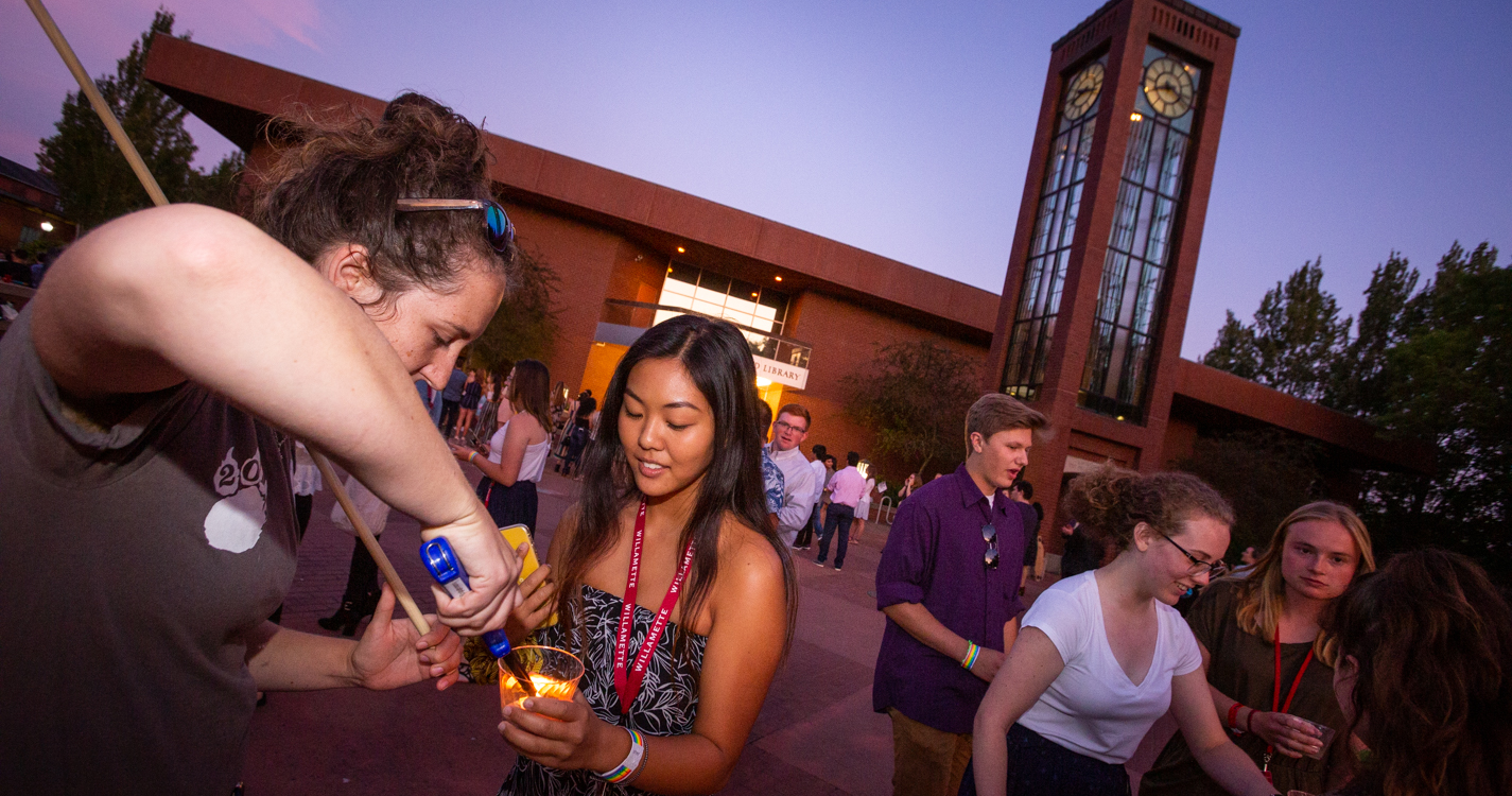 Two alumni light the votive candles held by incoming student at duck in Jackson Plaza