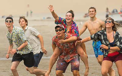 Students on the beach leap for a Frisbee