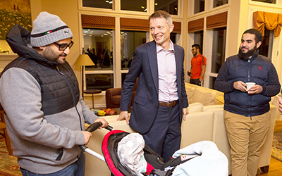 Faculty member talks to international students and their families at event he hosts at his house. 