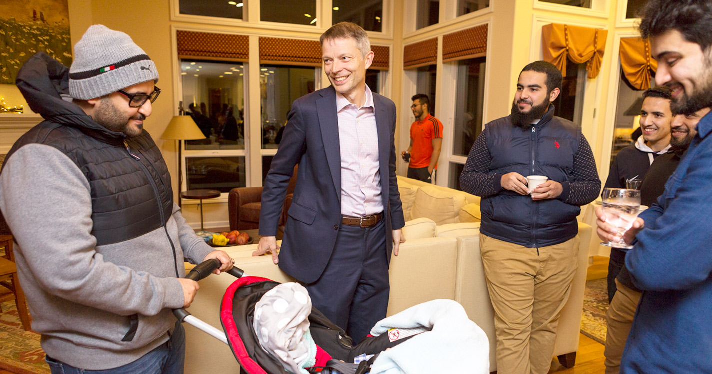 Faculty member talks to international students and their families at event he hosts at his house. 