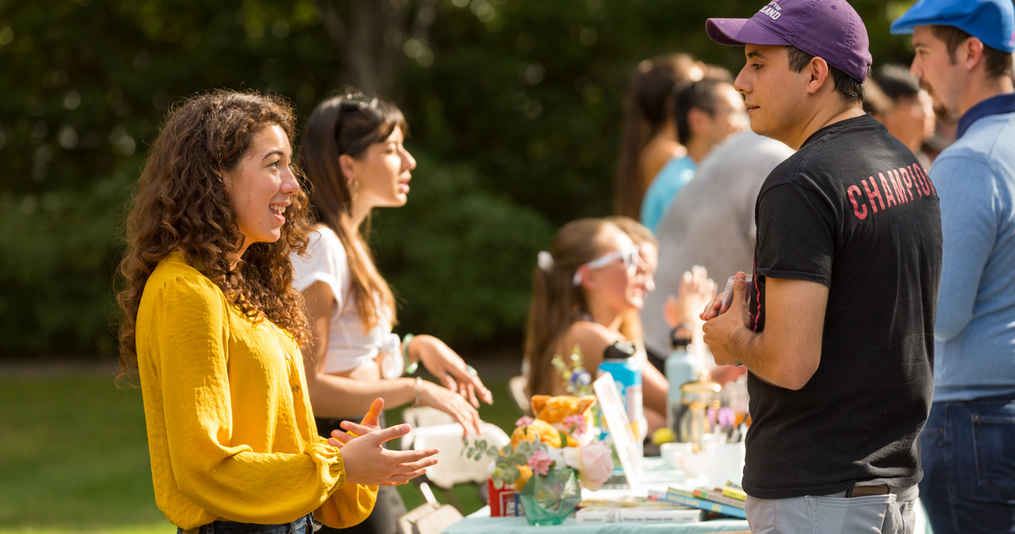 Two students stand on opposite sides of a display table discussing a student org