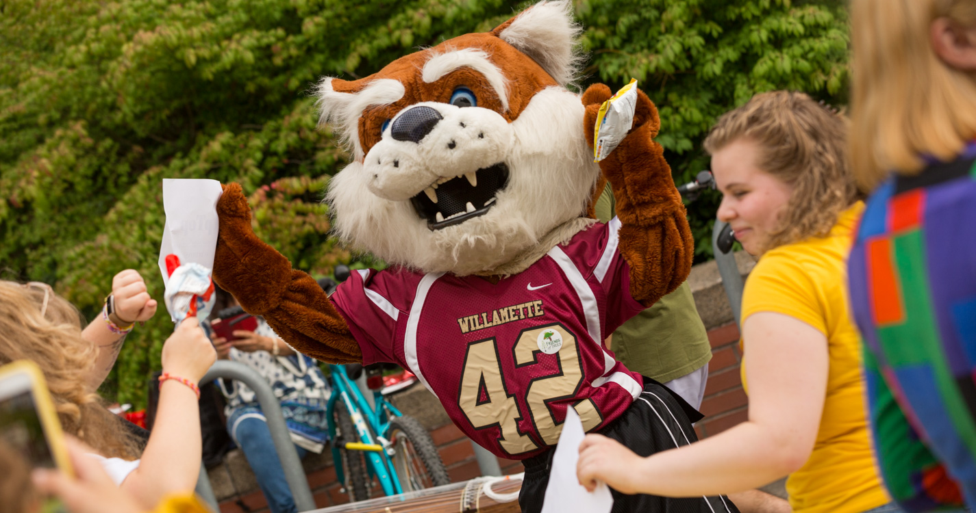 Blitz the Bearcat dances while holding a bag of potato chips